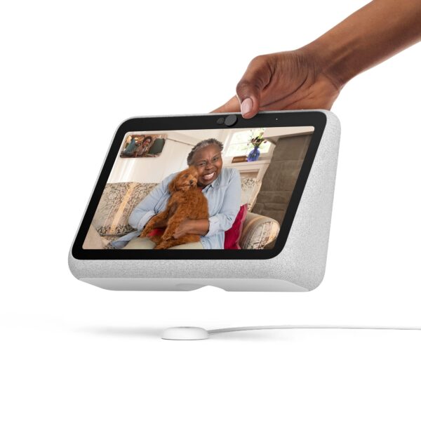 image of a person holding a device that has a screen displaying a live video call of a woman smiling and holding a puppy while sitting on a couch.